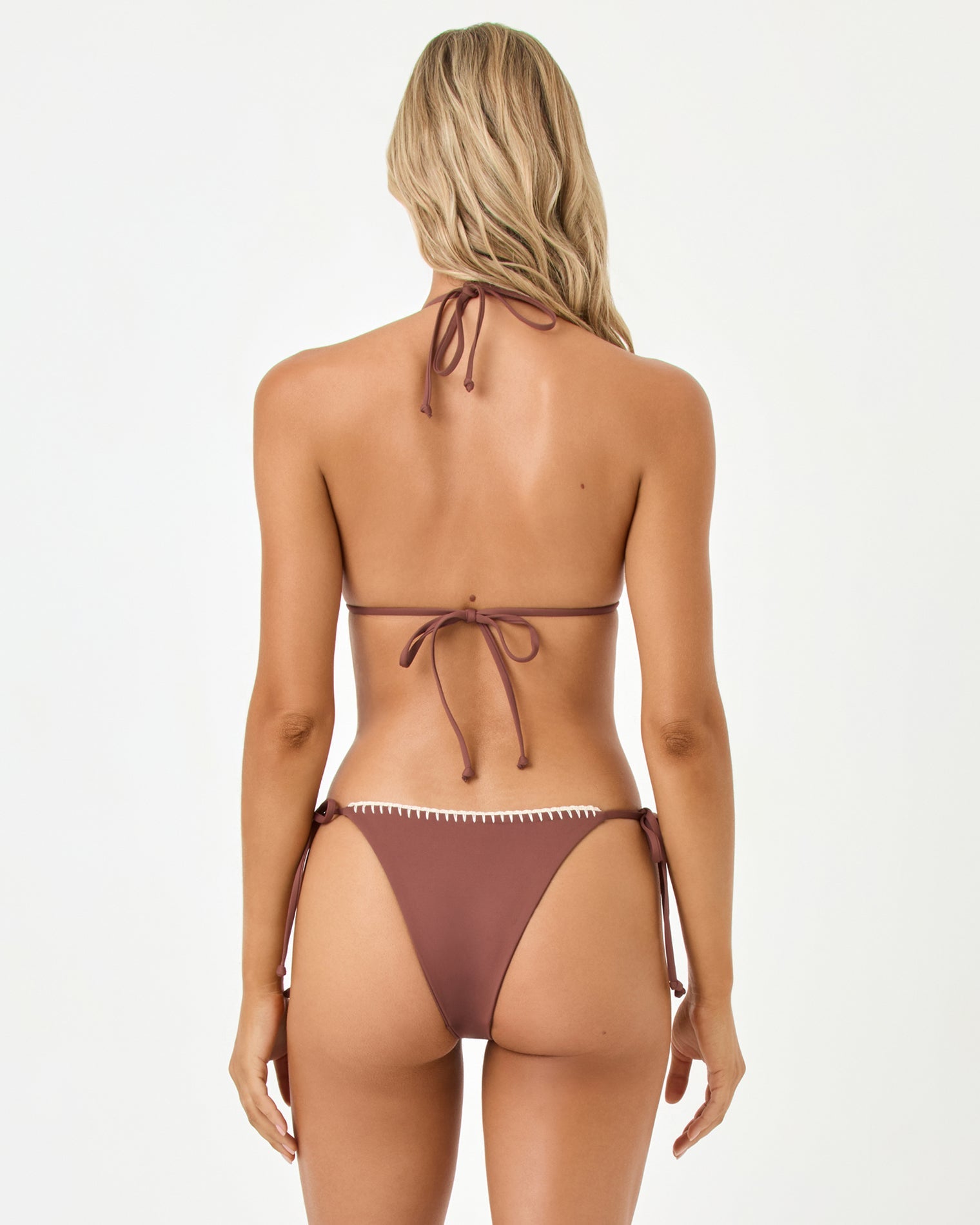 Back view of a woman wearing a brown bikini with white trim on a white background