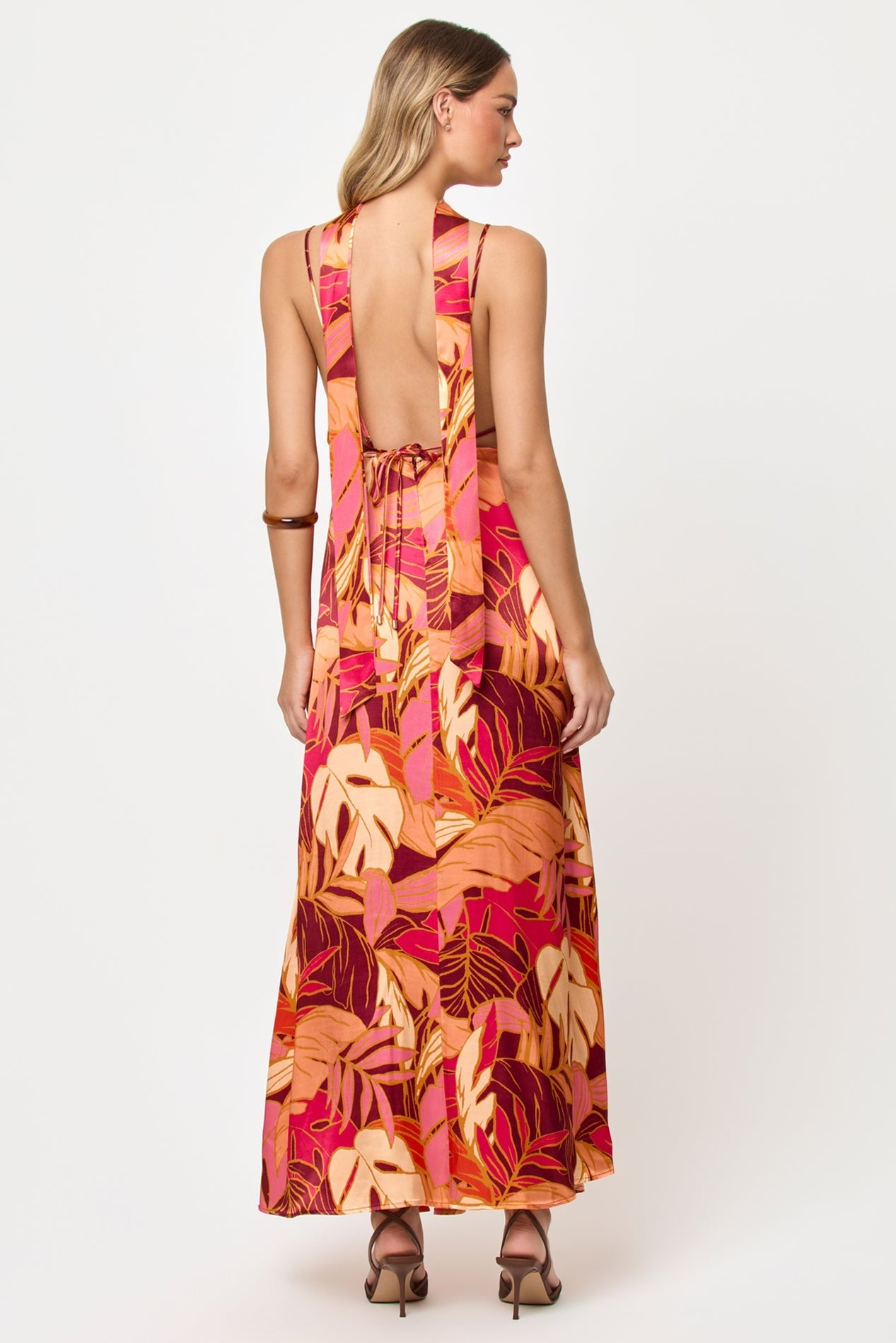 Back view of woman wearing a colorful floral dress on a white background