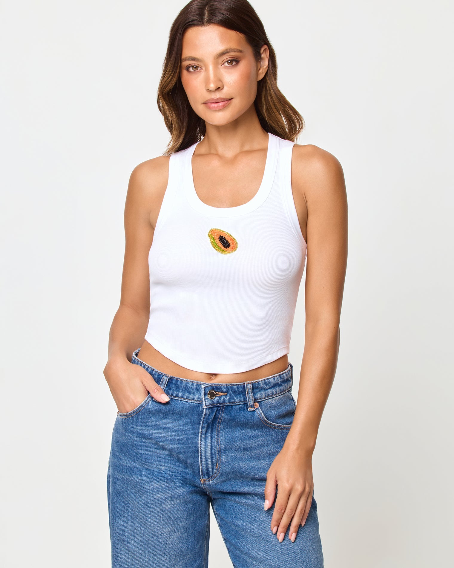 Papaya | Badge:New Arrival_#B2AC88_#ffffff'
Woman wearing a white tank top with a design and blue jeans on a plain background