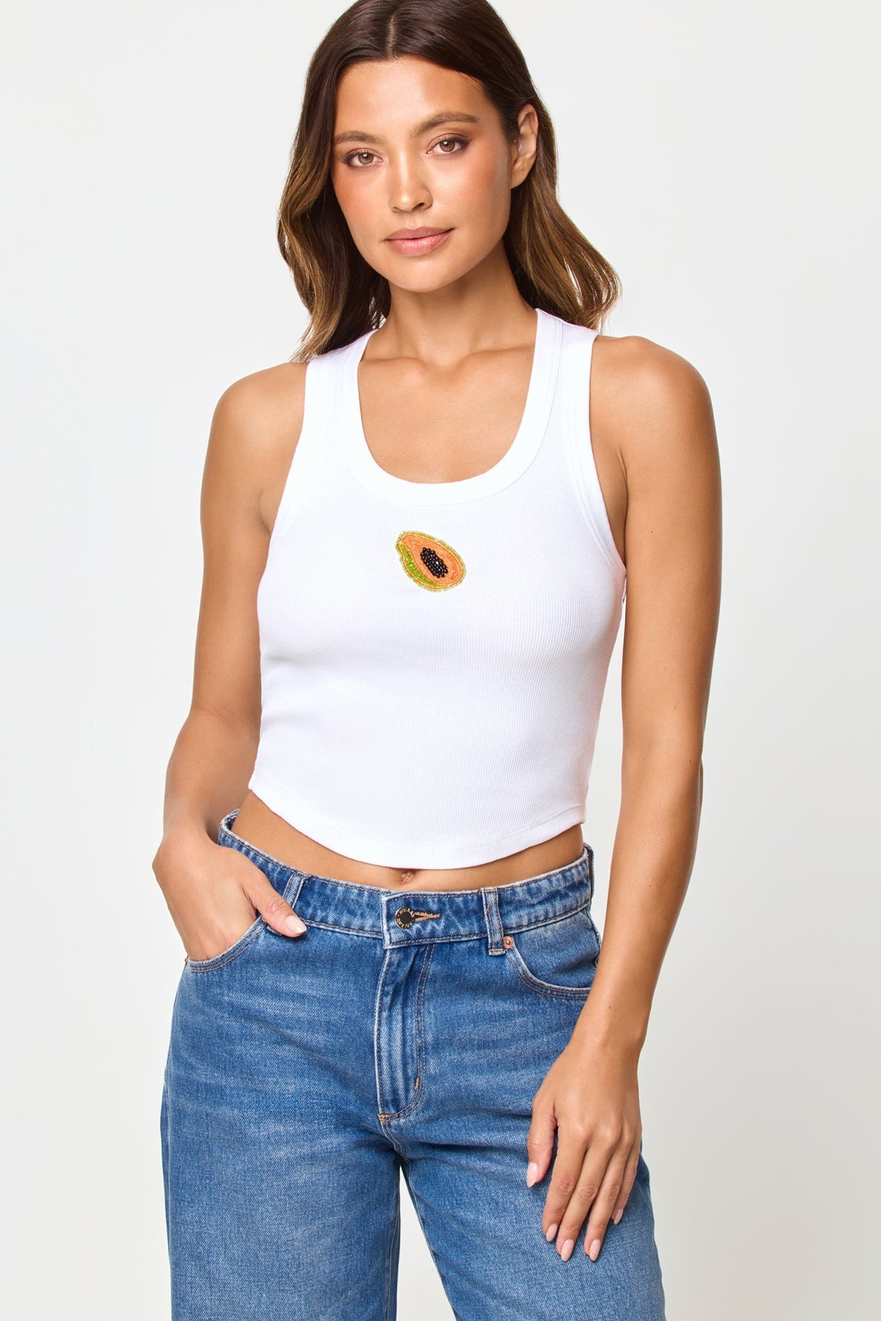 Papaya | Badge:New Arrival_#B2AC88_#ffffff'
Woman wearing a white tank top with a design and blue jeans on a plain background