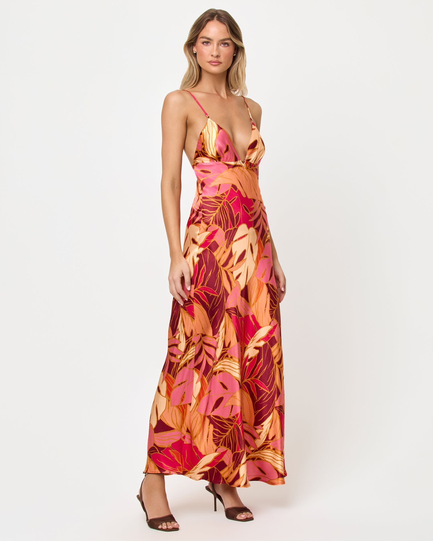 Side view of woman wearing a colorful floral dress on a white background