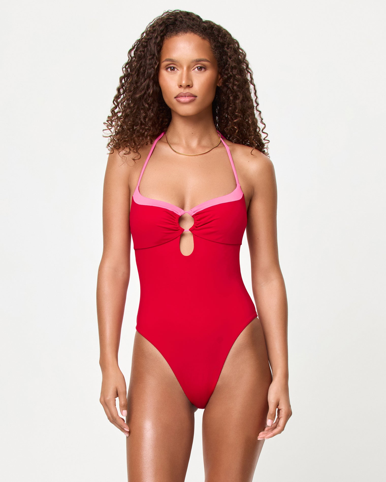 Woman wearing a red swimsuit with pink straps on a white background