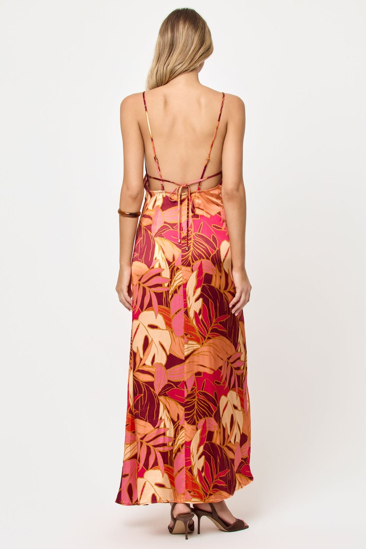 Back view of woman wearing a colorful floral dress on a white background