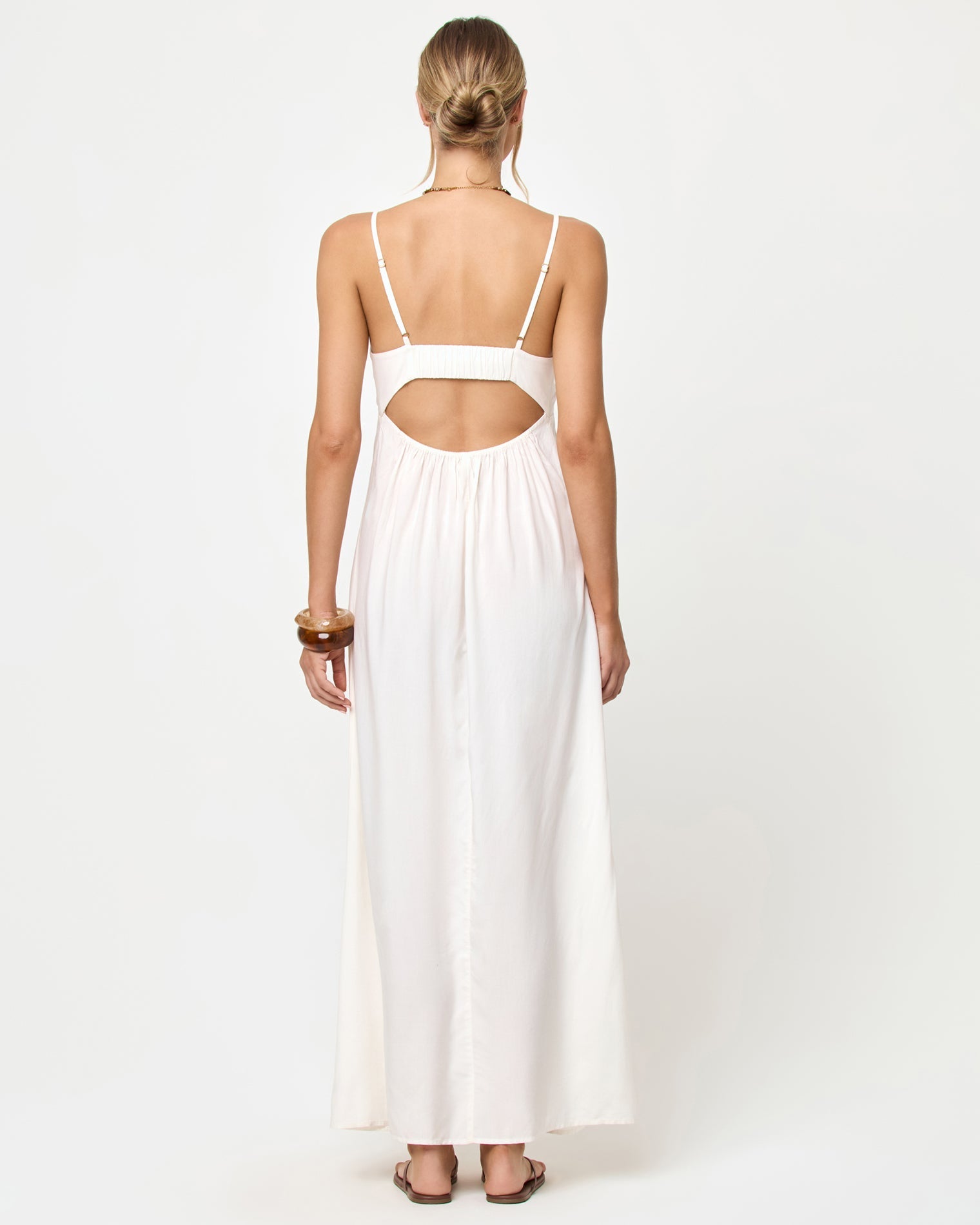 Woman wearing a white dress with cut-out back on a white background