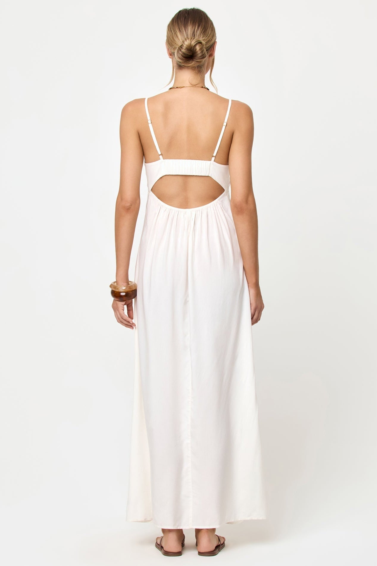 Woman wearing a white dress with cut-out back on a white background