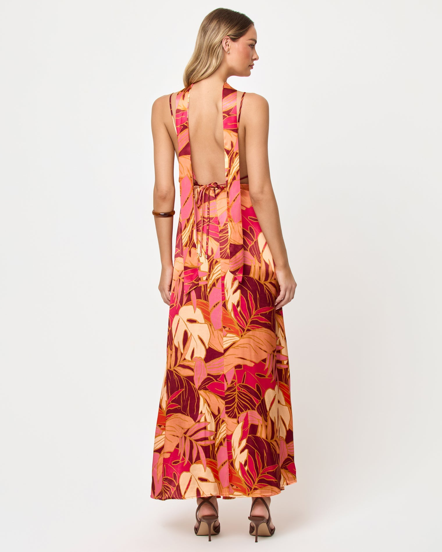 Back view of woman wearing a colorful floral dress on a white background