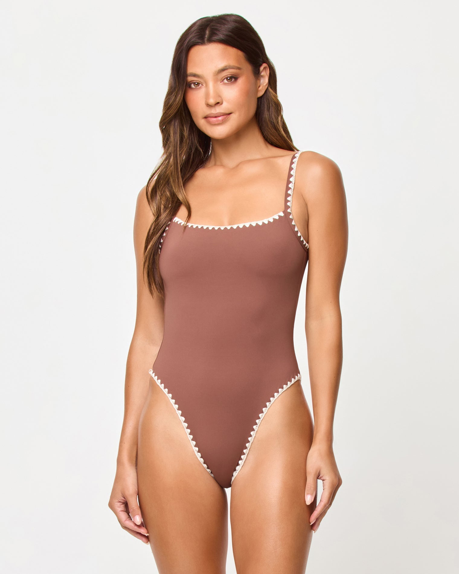 Woman wearing a brown one-piece swimsuit with white trim on a white background
