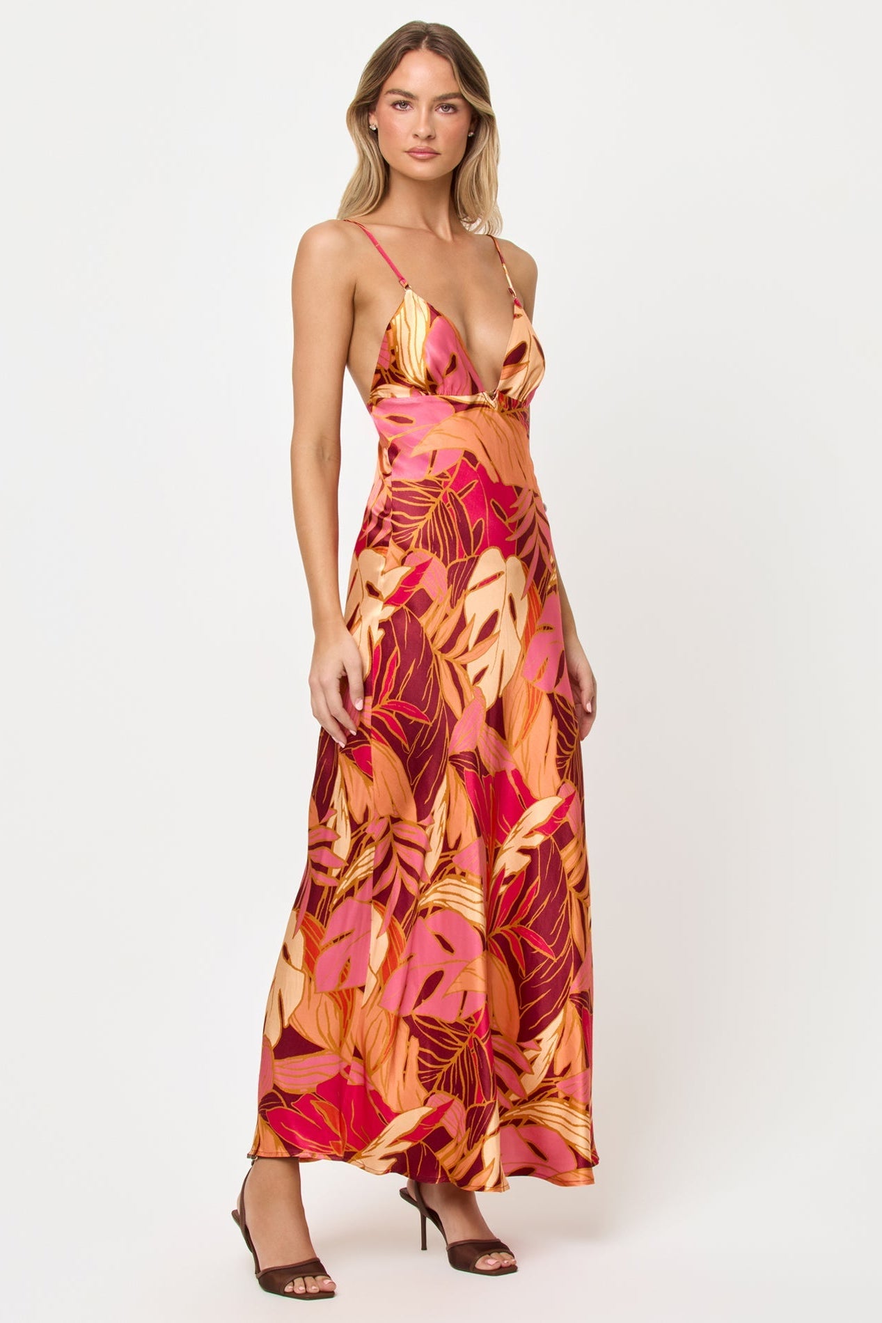 Side view of woman wearing a colorful floral dress on a white background