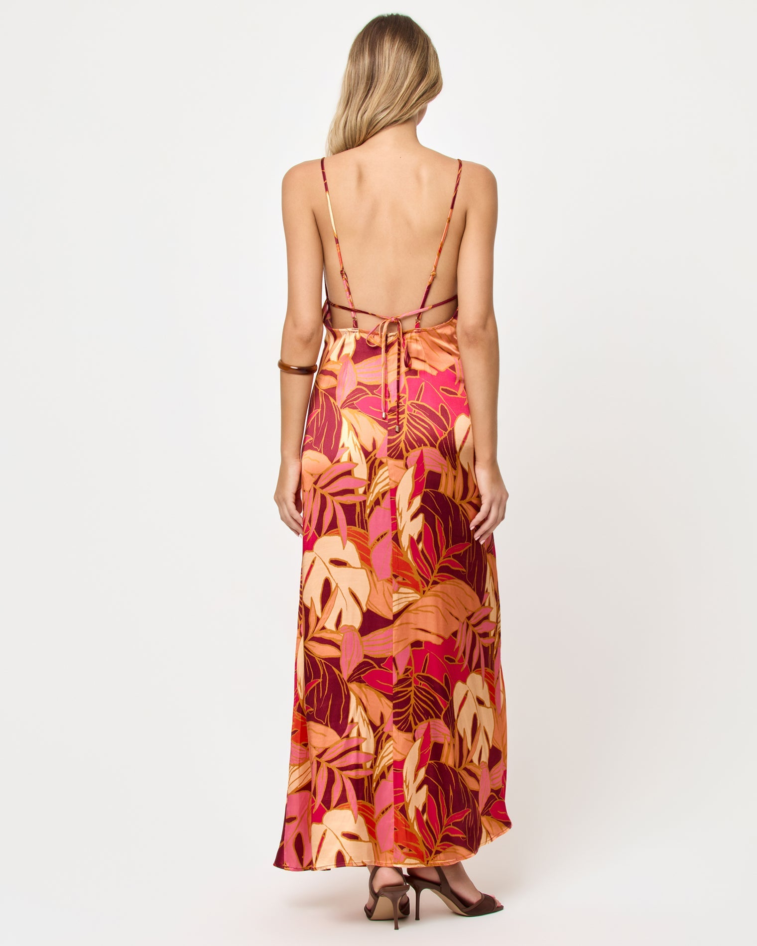Back view of woman wearing a colorful floral dress on a white background
