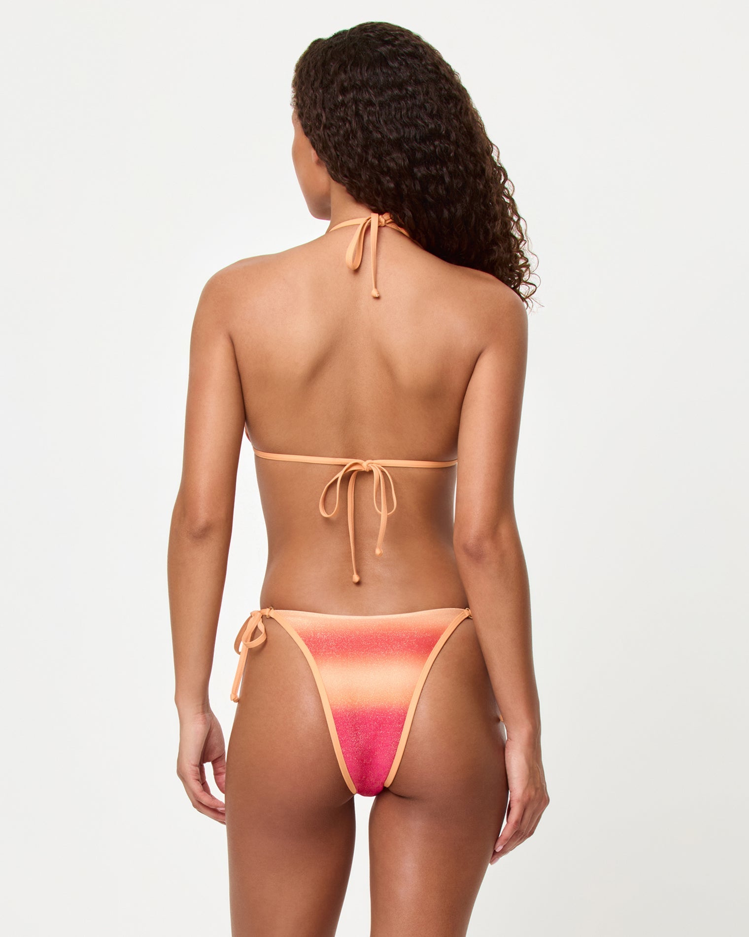 Back view of a woman wearing a two-piece swimsuit with a gradient design on a white background